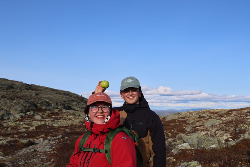 Ingvil og Per på fjelltur. Dei smiler, Per held opp eit eple.